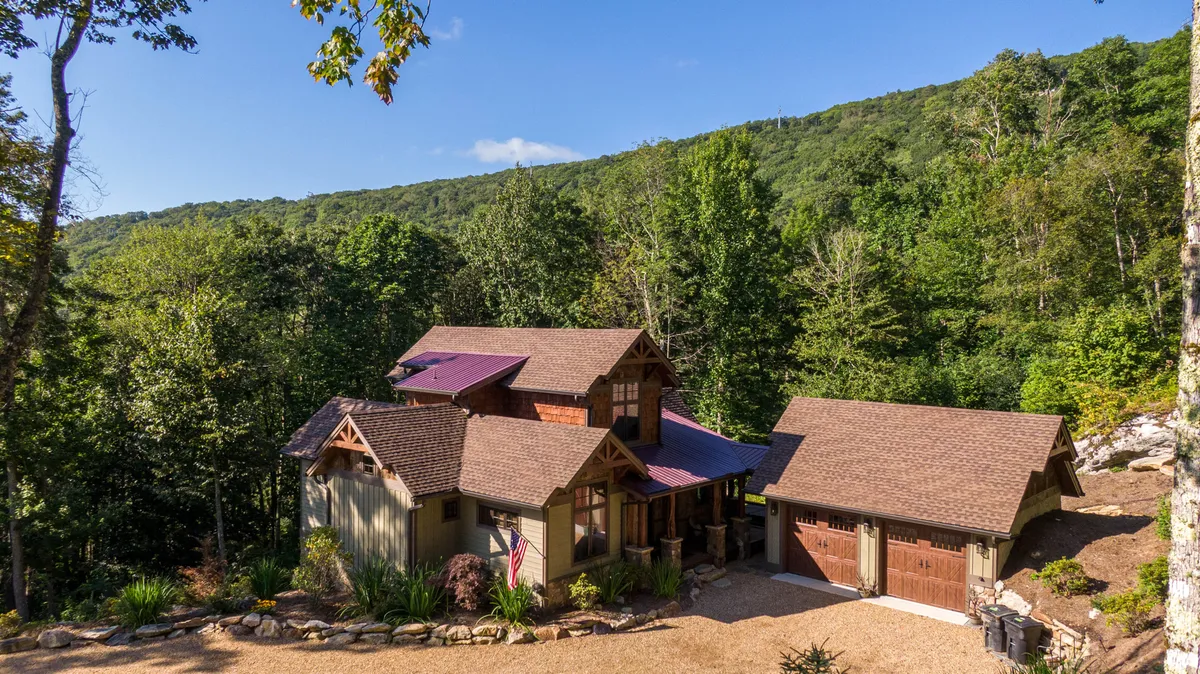 This exterior image features the main house and garage surrounded by a landscaped garden. The tranquil scene highlights plenty of green space and open sky, with a welcoming porch and pathways leading to outdoor areas ideal for gatherings, play, and relaxation.