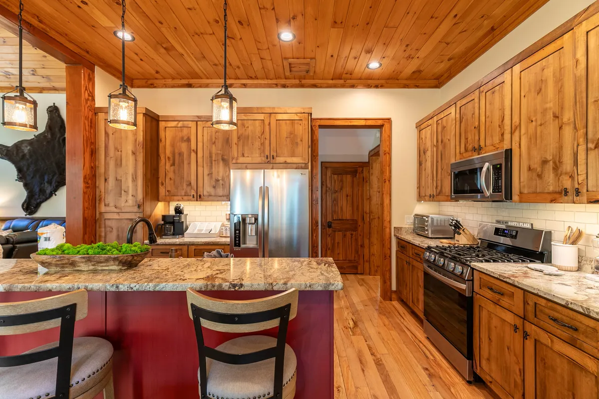 An open kitchen with granite countertops, wooden cabinetry, stainless steel appliances, and stylish light fixtures. The space invites guests to cook together, entertain, and enjoy group activities centered around food and conversation.