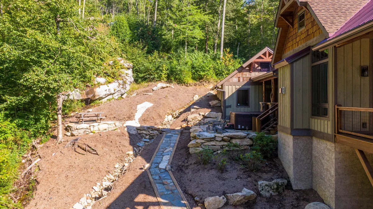 An exterior scene featuring a stone pathway, lush greenery, and the building's facade. The patio and surrounding garden areas suggest ample space for group gatherings, evening conversations, and outdoor activities like those mentioned in the section. The mood is tranquil and inviting.
